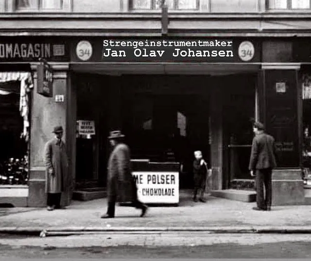 Sort-hvitt bilde av en bygård med skiltet «Strengeinstrumentmaker Jan Olav Johansen» over inngangen.
